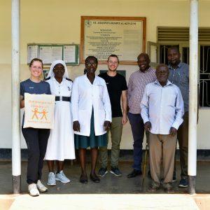 Eine Gruppe von sieben Personen posieren vor einer Wand eines Krankenhauses